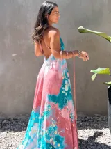 Vestido largo de tela fluida, color verde esmeralda con estampado abstracto en tonos turquesa y detalles dorados. Diseño asimétrico con un solo tirante tejido en el hombro.