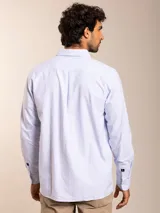 Camisa celeste a rayas verticales blancas, de corte regular fit, con cuello abotonado, manga larga y bolsillo en el pecho con logo bordado.