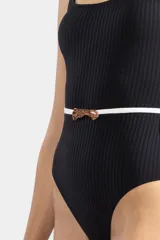 Traje de baño entero negro con textura acanalada y cinturón blanco con hebilla metálica.