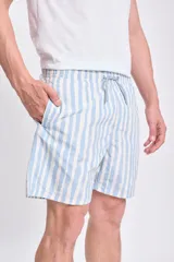 Short de baño celeste con rayas verticales blancas con efecto acuarela, cintura elástica y cordón ajustable.