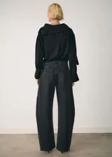 Pantalón de jean negro de corte wide leg, tiro bajo y bajo deshilachado. Cuenta con cierre de cremallera y botón, trabillas, cinco bolsillos y costuras decorativas.