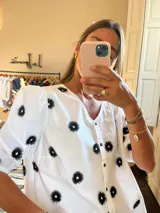 Camisa blanca con estampado de flores negras, cuello en V y mangas 3/4 abullonadas.