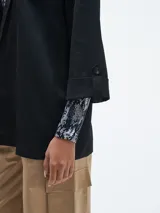 Blazer negro de corte recto, sin cierre y mangas 3/4 con botón.