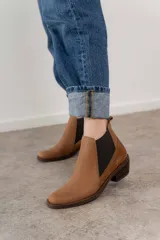 Botín negro de cuero con paneles laterales de gamuza y elástico en los tobillos. Tiene un pequeño taco cuadrado.