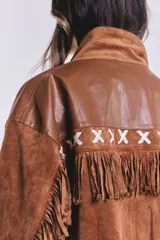 Campera marrón de gamuza con flecos y detalles en cuero sintético en la parte superior. Corte suelto.