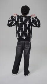 Sweater de punto negro con diseño de cruces blancas, cuello redondo y bordado con la palabra "Starrr" en el pecho.