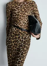 Blusa fluida de poliéster con estampado animal print, corte recto, cuello redondo, mangas largas y cierre de botón en la parte posterior.