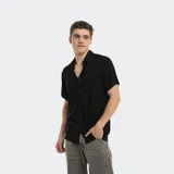 Camisa negra de manga corta con cuello clásico y cierre frontal con botones. Diseño liso y corte regular.