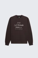 Sudadera marrón de Zara con cuello redondo y mangas largas. Estampado frontal con el logo de Zara, la leyenda "A Coruña Established 1975" y la dirección "Rúa Juan Flórez 64-66".