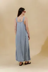 Vestido largo de jean celeste con breteles anchos, corte recto, abertura lateral y bolsillo plaqué en el pecho.