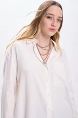 Camisa blanca de lino de manga larga con cuello clásico, cierre frontal con botones y bolsillo en el pecho.