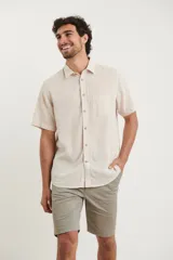 Camisa sport de manga corta color verde oliva, línea premium, con cuello clásico, cierre frontal con botones de coco y bolsillo de parche en el pecho. Confeccionada en lino y algodón.