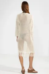 Cárdigan largo de punto abierto color crema con flecos en el ruedo y lazo de ajuste en el escote.