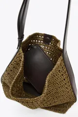 Bolso tipo saca de rafia color marrón con asa de hombro ajustable y detalle lateral. Incluye cartera con bolsillo extraíble y cierre con botón imantado.