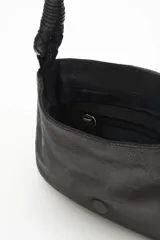 Cartera bandolera de cuero vacuno color negro, con correa trenzada y solapa con diseño calado y tachas. Incluye pañuelo estampado atado al asa.