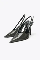 Zapato destalonado color gris oscuro con efecto acharolado, punta fina, cierre con tira trasera ajustable con hebilla y tacón alto fino de 11 cm.