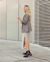 Botín corto de cuero negro, estilo cowboy moderno, con textura de cocodrilo en la caña y puntera cuadrada. Posee un tacón ancho y geométrico, y cierre lateral.