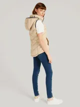 Chaleco acolchado Tommy Hilfiger color beige con capucha ajustable con cordones y cierre de cremallera frontal. Cuenta con bolsillos laterales con cremallera y detalles distintivos de la marca.