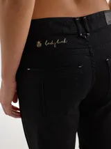 Pantalón negro de gabardina con alforzas verticales en los laterales y aberturas en el ruedo.