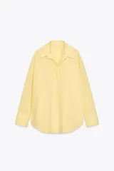 Camisa amarilla de popelina de algodón, con cuello solapa, escote en pico, manga larga con puños y cierre frontal con botones.