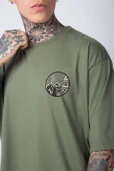 Remera color ladrillo de corte oversize, con cuello redondo y mangas cortas. Estampado pequeño en el pecho con un diseño circular en blanco y negro.