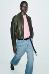 Chaqueta estilo bomber de efecto piel en color verde oliva, con cuello solapa, cierre frontal con cremallera, mangas largas y bajo con acabado elástico.