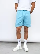 Bermuda gris de felpa sin friza, con cintura elástica ajustable con cordón y logo Umbro estampado en rojo en la pierna izquierda.