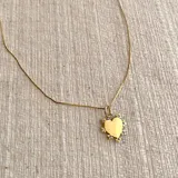 Collar en acero dorado con dije en forma de corazón decorado con circonitas.