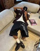 Camisa negra a cuadros rojos con estampado de estrellas y logo de la marca en la espalda.