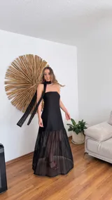 Vestido largo negro de tejido de punto con escote recto y breteles finos. La falda es de encaje transparente. Incluye una bufanda fina al tono.