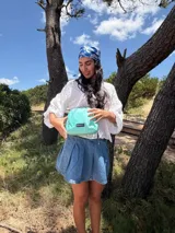 Bandolera pequeña de tela negra, con correa ancha ajustable y cierre superior.