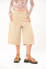 Bermuda de jean color beige, tiro medio, con bolsillos delanteros y traseros.