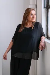 Blusa negra de gasa con mangas cortas y detalle de lentejuelas en el ruedo y las mangas.