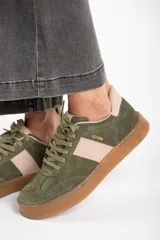 Zapatilla deportiva de cuero color verde oliva con detalles en rosa y suela marrón.