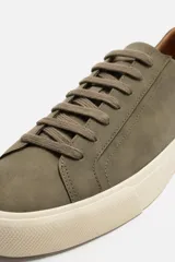 Zapatillas urbanas grises de caña baja, con cordones, puntera redondeada, forro interior en contraste y suela con ligera textura.