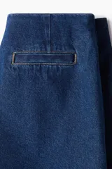 Short pollera cruzado de tiro alto en sarga de algodón color azul denim con botón a un lado, cierre oculto adelante y bolsillos insertados decorativos atrás.