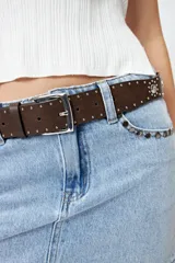 Cinturón negro de cuero sintético con hebilla metálica plateada y apliques de tachas plateadas con forma de corazón y circulares.