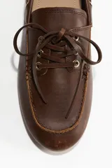 Zapatos náuticos de cuero marrón con cordones y costura de mocasín adelante. Forro en lona de algodón.