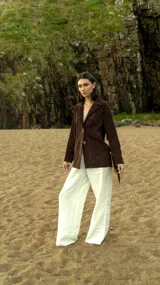 Blazer marrón de gamuza ligera con flecos largos en las mangas y botones de cuerno. Corte recto y bolsillos frontales.