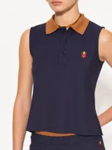 Musculosa roja de piqué de punto con cuello tipo polo marrón, sin mangas y calce cómodo. Incluye detalle bordado de vaquita de San Antonio en el frente.