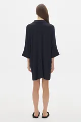 Camisola negra larga tipo vestido, de manga tres cuartos y cuello camisero. Tiene botones delanteros ocultos.