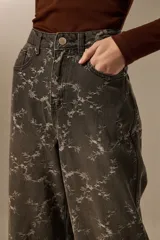 Pantalón de jean azul claro con estampado abstracto desgastado, corte baggy y tiro medio.