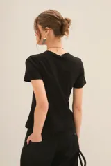 Remera color crudo de algodón con estampado de leopardo, hojas de palma y texto 'Rock in the wind'.