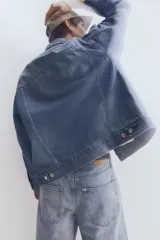 Campera de denim celeste con cuello clásico, cierre frontal con botones metálicos, bolsillos con solapa en el pecho y bolsillos laterales. Corte holgado.