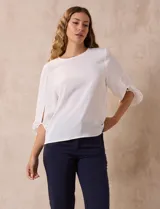Blusa de gasa color blanco con estampado de hojas verdes, de mangas 3/4 abullonadas con puños elásticos.