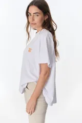 Remera blanca de algodón con estampado de tres jarrones con flores rojas y la frase "The Flowers Club" en azul.