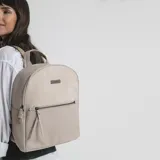Mochila color marrón claro, combinada con apertura frontal y bolsillo interior. Tiene asa de mano y correas de galón regulables para colgar en la espalda.