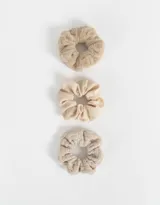 Set de tres scrunchies de pelo en tonos beige, con diferentes texturas: una de piel sintética, una de tela lisa y una tejida.